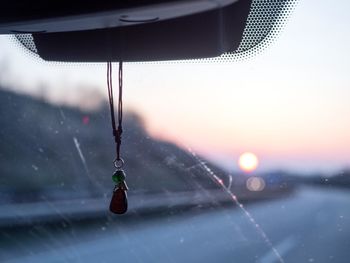 Close-up of wet windshield against sky during sunset