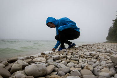 Full length of man on rock in sea against sky