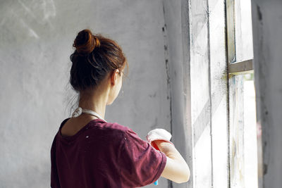 Rear view of woman standing against wall