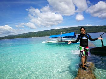 Full length of smiling woman in sea against sky