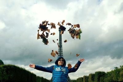 Low angle view of woman standing against cloudy sky