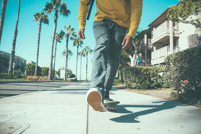 Low section of man walking on street in city