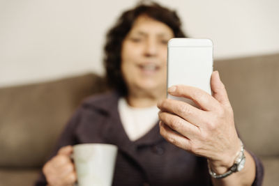 Senior woman using smart phone sitting at home