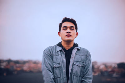 Portrait of young man looking away against sky