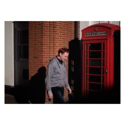 Full length of man standing against red brick wall