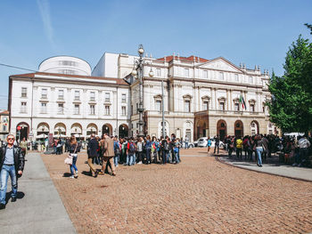 People on street against buildings in city