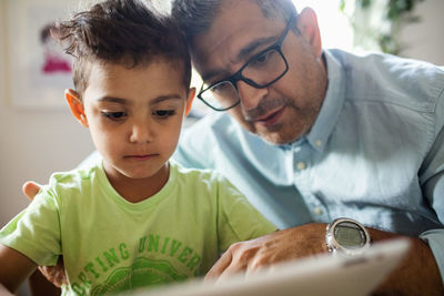 Father and son using digital tablet at home