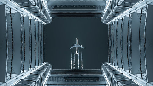 Directly below shot of building against airplane in clear sky