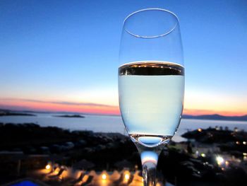 Close-up of wineglass against sky during sunset