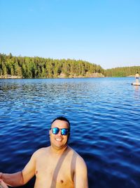 Portrait of shirtless man in lake against sky