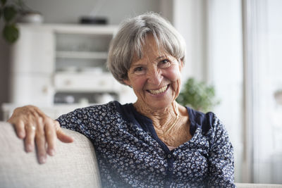 Portrait of happy senior woman sitting on couch at home