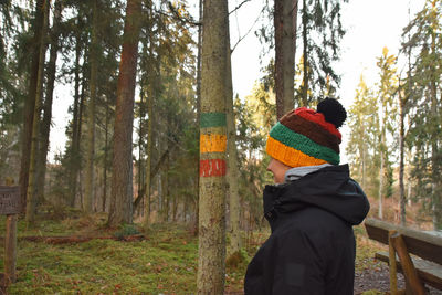 Rear view of person standing by trees in forest