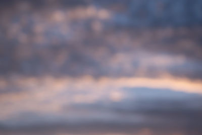 Defocused image of sea against sky at sunset