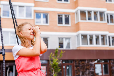 Young woman standing against building