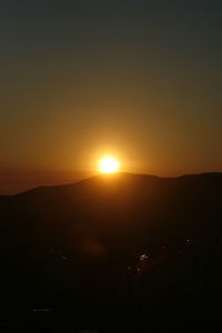 Scenic view of silhouette mountains against orange sky