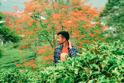 Full length of young woman looking away against trees