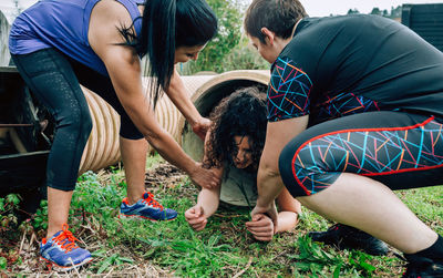 Women helping friend in coming out of pipe