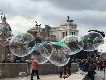 People at bubbles against sky