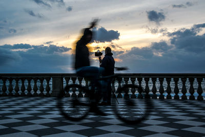 People by sea against sky during sunset
