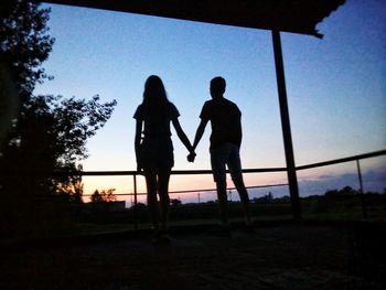 Silhouette couple standing on landscape against clear sky