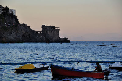 Boats moored on sea against sky during sunset