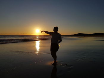 Man standing on beach against sky during sunset