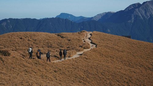 Rear view of people walking on arid landscape