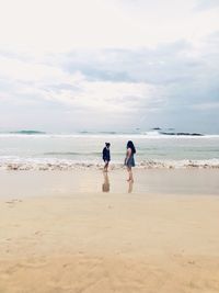 Women at beach against sky