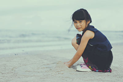 Portrait of girl playing on sand at beach