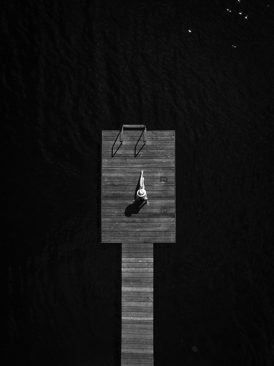 Aerial view of woman sitting on pier over lake