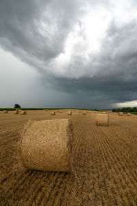 Hay bales on field against sky