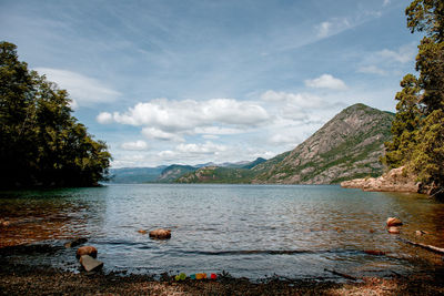 Scenic view of lake by mountains against sky