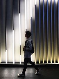 Side view of man standing against illuminated wall