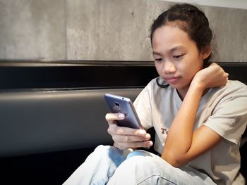 Girl using mobile phone while sitting at home