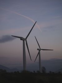 Windmills on landscape against sky during sunset