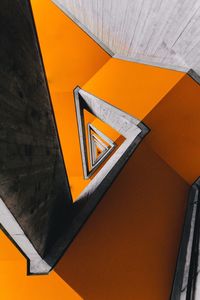 Low angle view of arrow sign on orange wall