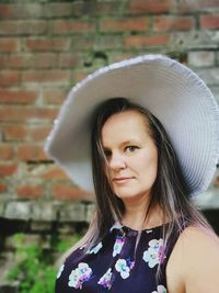 Portrait of mid adult woman wearing hat against wall