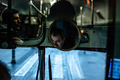 Reflection of man sitting on glass window of train