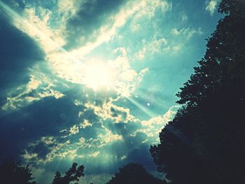 Low angle view of trees against cloudy sky