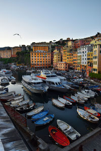 High angle view of boats moored at harbor against buildings in city