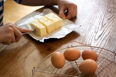 Cropped hands of woman holding butter on table