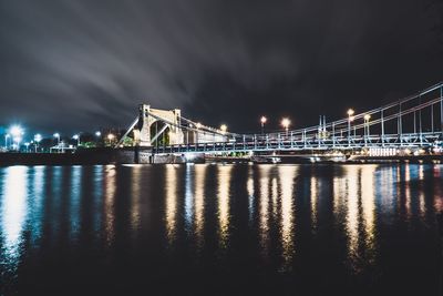 Illuminated bridge over river at night