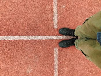 Low section of man standing on running track