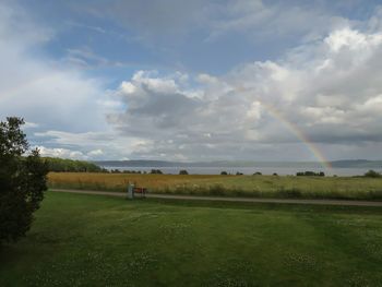 Scenic view of grassy field against cloudy sky