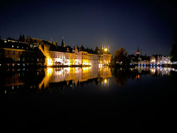 Night view of the mauritshuis museum in the hague. reflection of illuminated buildings in water