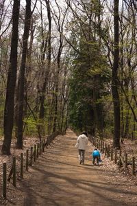 Rear view of woman walking on footpath in forest