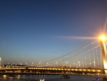 Illuminated bridge over river against sky in city