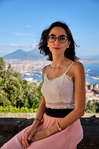 Portrait of beautiful young woman sitting against sky