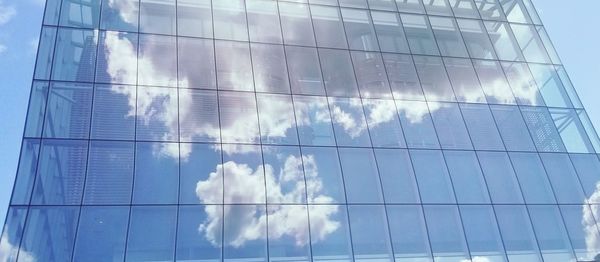 Digital composite image of glass building against cloudy sky