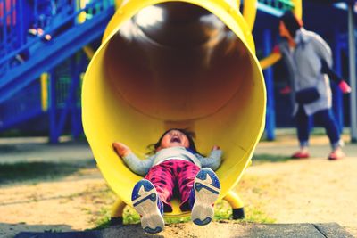 Full length of boy lying in outdoor play equipment at playground